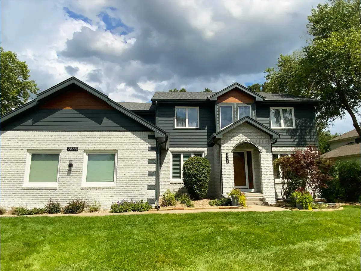 Elegant two-story house with light siding and dark trim, showcasing a refreshed and modernized appearance.