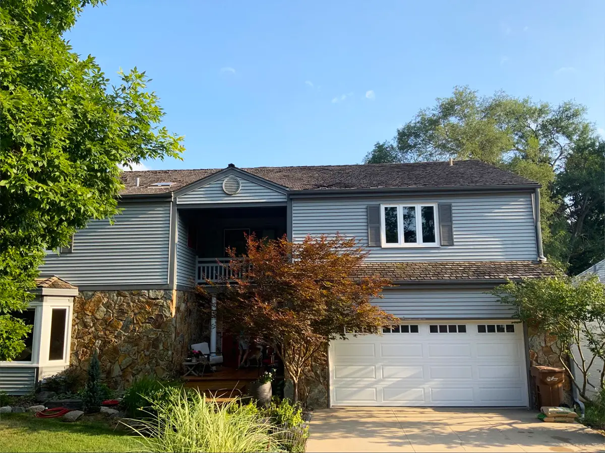 Two-story home with an aging roof showing wear and discoloration, ready for replacement.