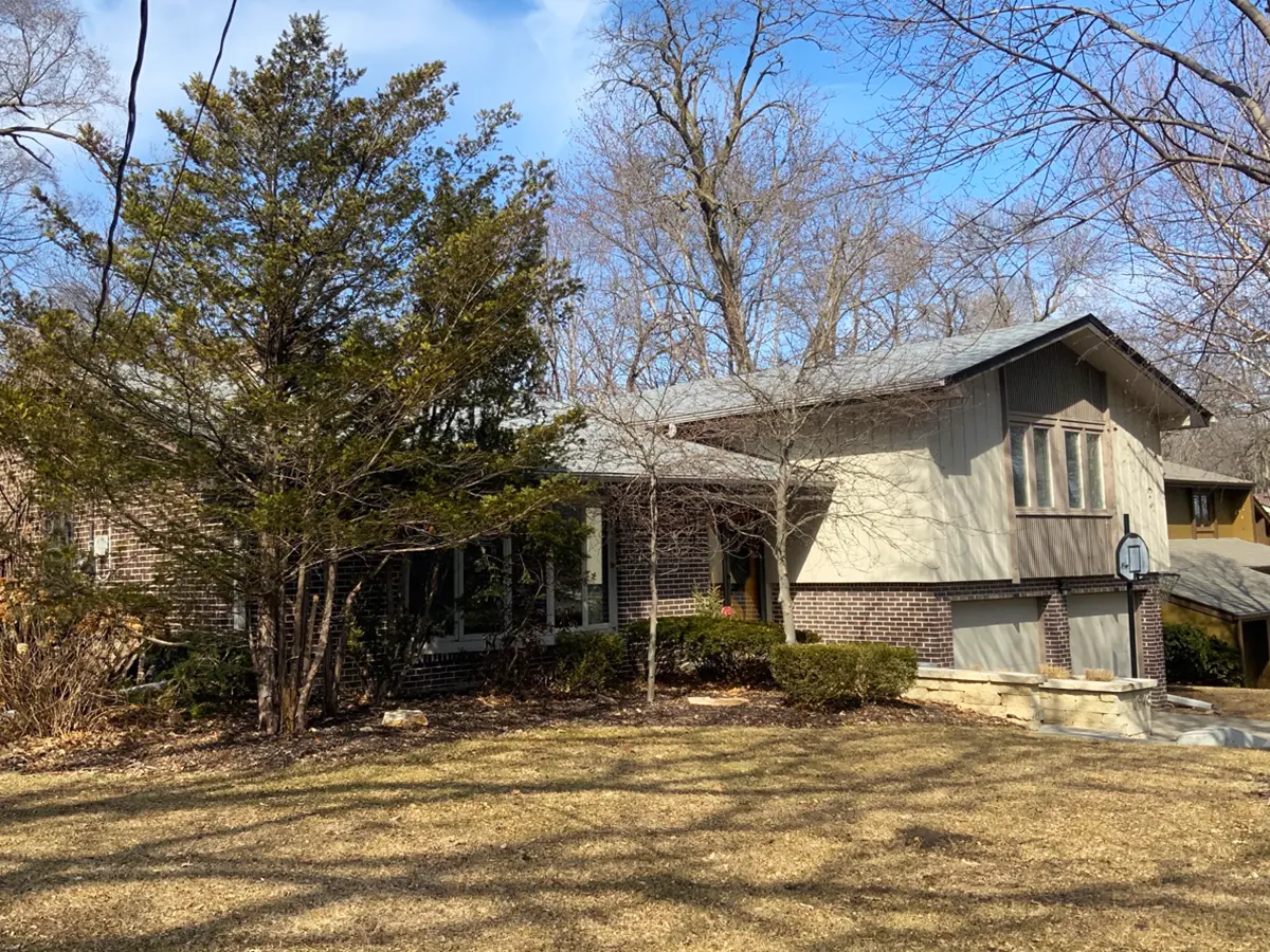 A suburban home with worn siding and overgrown landscaping, ready for siding replacement.