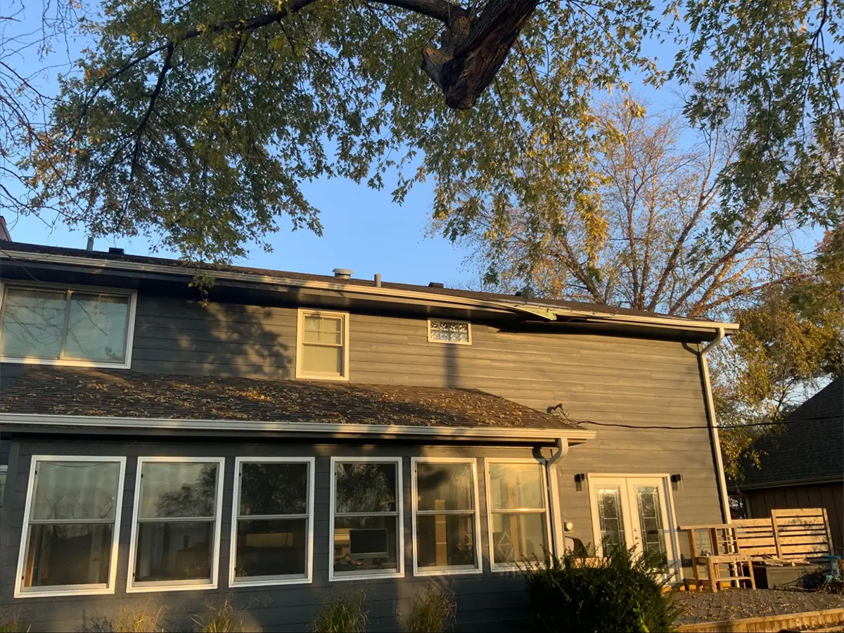 Two-story home with damaged siding and outdated windows needing repair and modernization.