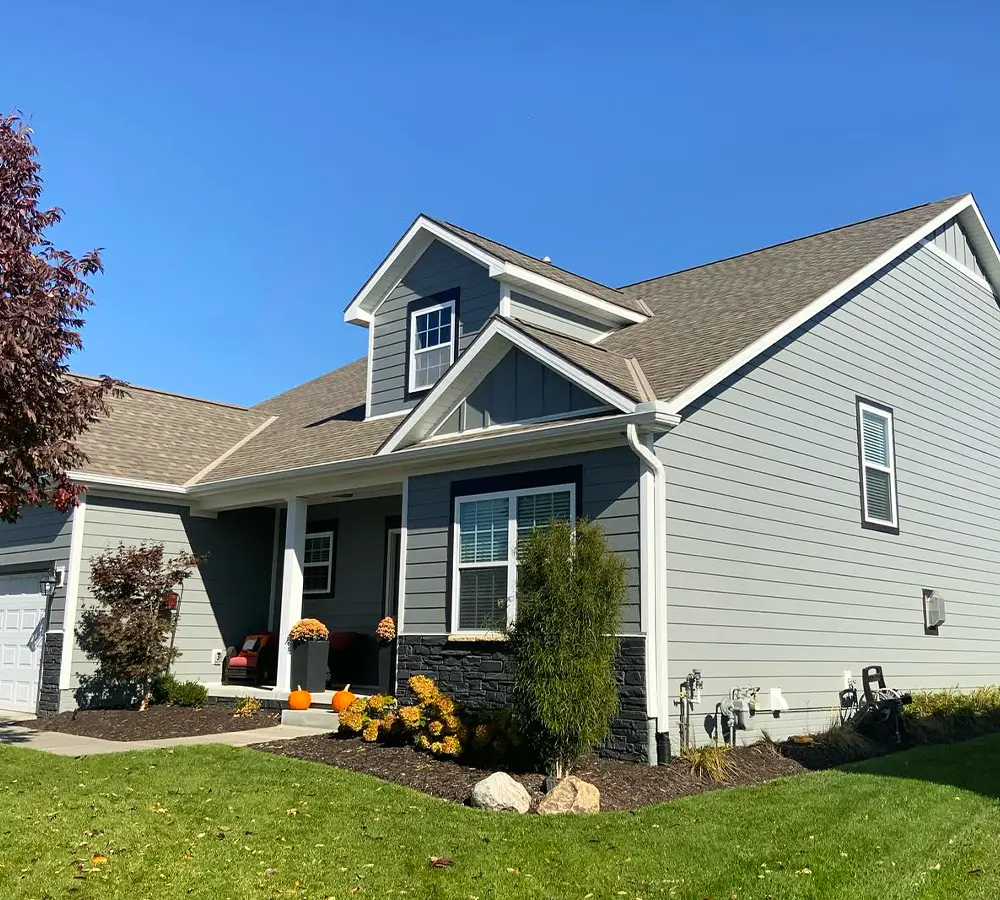 Photo of a house with modern siding and well-maintained landscaping under a clear blue sky.