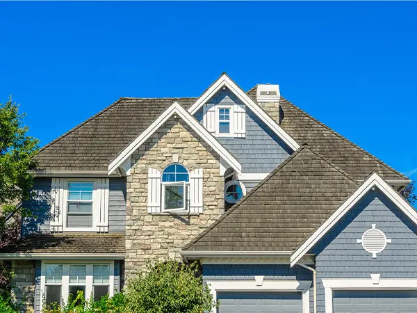 Completed roof installation on a two-story stone and siding home, showcasing a modern and durable design.