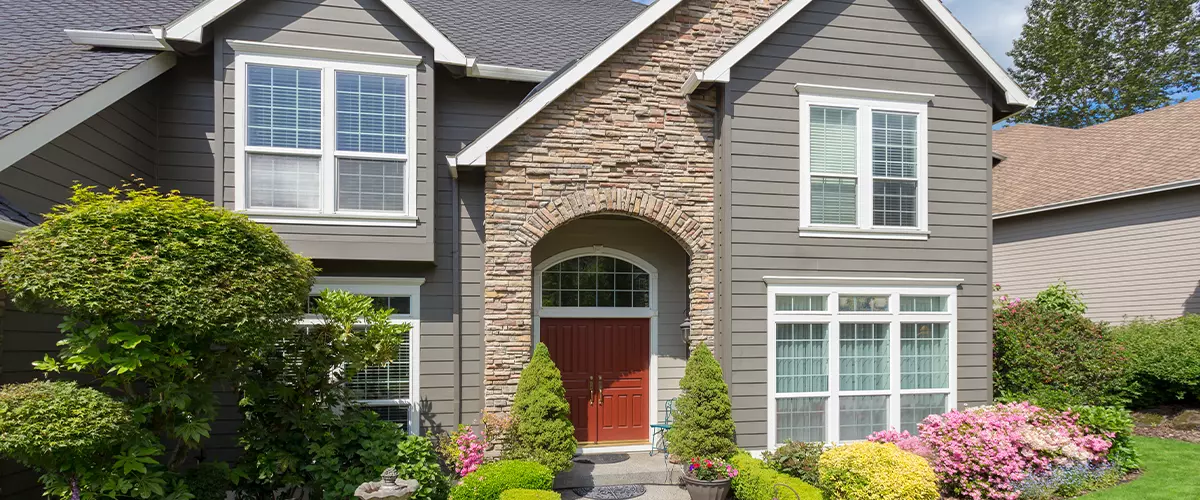 Beautiful home exterior with colorful plants on bright and sunny spring day, stone siding