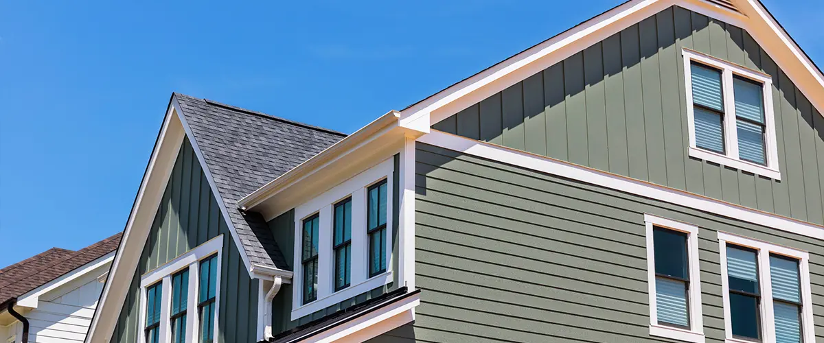 Beautiful modern house with green and white board and batten siding and asphalt shingle roofing.