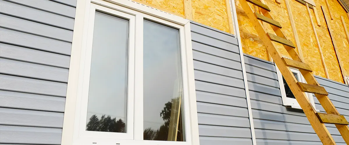 Close-up of home exterior siding installation with a window, showing construction progress.