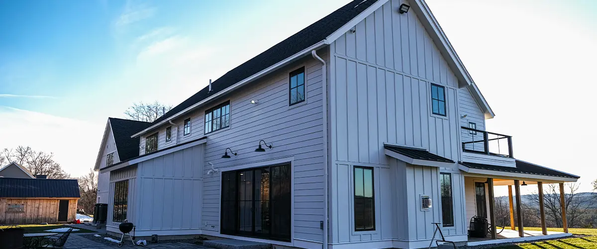 Modern farmhouse with white board and batten siding, black windows, and covered patio.