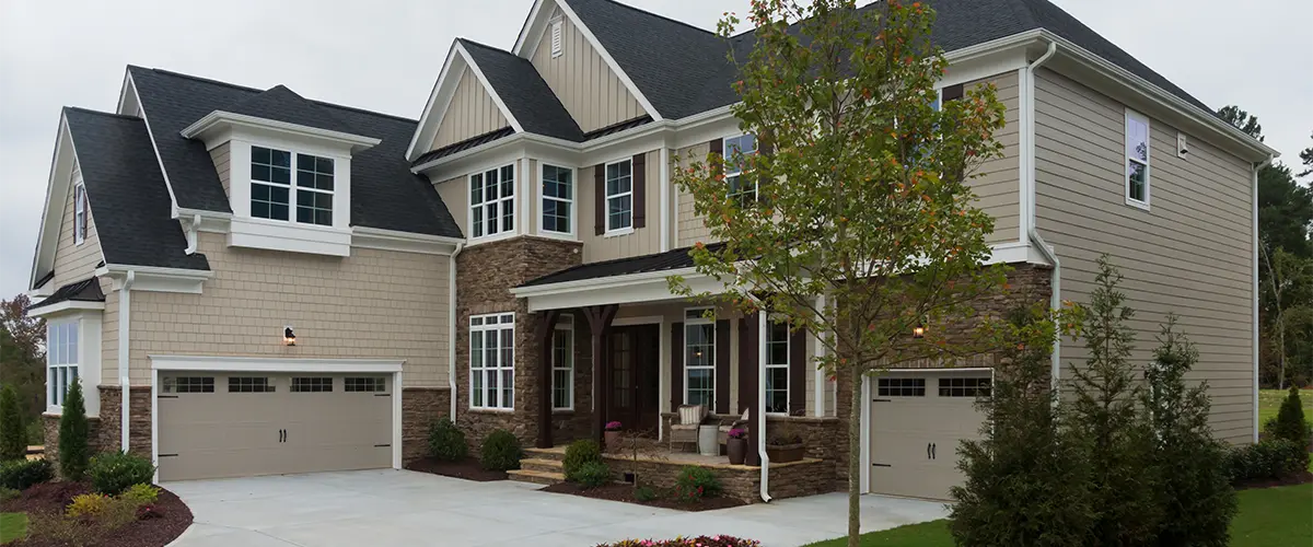 Luxury home with modern siding, black roof, and a concrete driveway, featuring energy-efficient windows and a landscaped front yard.